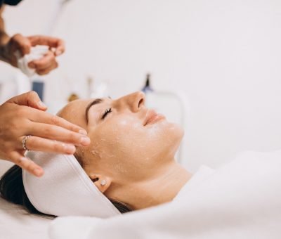 cosmetologist cleaning face of a woman in a beauty salon